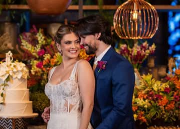 Casal em trajes nupciais; bolo e flores; Bride's Dream ao fundo.